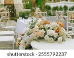 White table with chairs and a floral arrangement in the center, set up for a wedding or a special event.