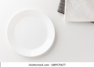 The white table had a white empty plate over the tablecloth. Place for placing text.