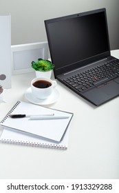 White Table With Laptop For Remote Work Or Study. Black Laptop With Blank Display Layout Template On Gray Background. Office Pc Desk Workspace In Home Interior