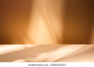 White table on brown wall background. Composition with leaves shadow on the wall and light reflections. Mock up for presentation, branding products, cosmetics food or jewelry.