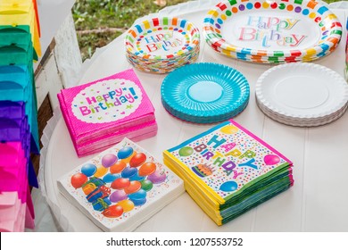 White Table Served With Disposable Tableware, Colorful Napkins And Paper Plates, Ready For Birthday Party. Close Up.