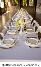 White tablecloth, table setting, glassware, white plates, gold forks, silver knives, flower vase, napkins, elegant dining, restaurant table, guest table, fancy table setting, event decor, wedding 