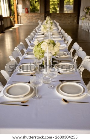 White tablecloth, table setting, glassware, white plates, gold forks, silver knives, flower vase, napkins, elegant dining, restaurant table, guest table, fancy table setting, event decor, wedding 