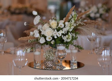White tablecloths with clear vases and white chrysanthemum and fern arrangements. Golden colored plates, peavh napkins, table numbers and mirror centerpieces. Wedding day