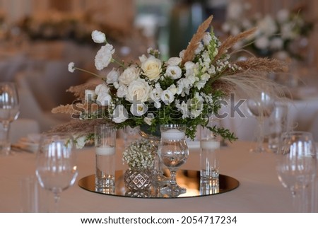 White tablecloths with clear vases and white chrysanthemum and fern arrangements. Golden colored plates, peavh napkins, table numbers and mirror centerpieces. Wedding day