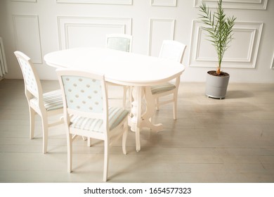 White tables and chairs for dinner in a classic interior. Upholstered chairs for comfortable sitting at the table