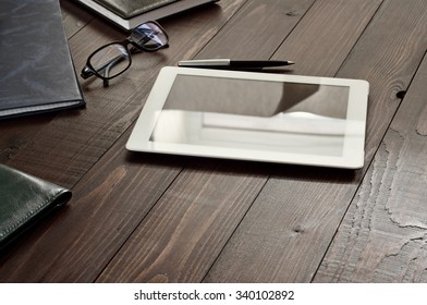 White tablet computer with office objects on office wooden table. Copy space. Free space for text