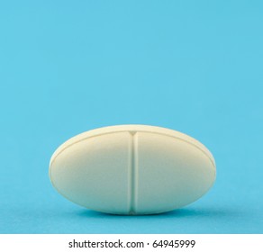 White Tablet On A Blue Background. A Photo Close Up