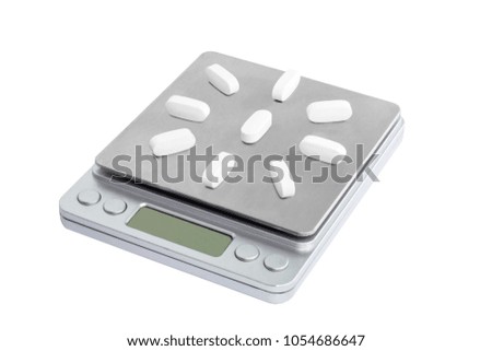 White tablets, vitamins, antibiotics gray electronic scales. Isolated. Concepts importance, weight is healthy.