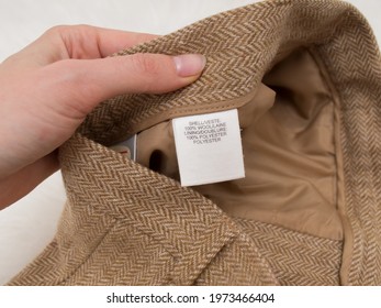 White Tag With Fabric Composition On Beige Clothes Close Up