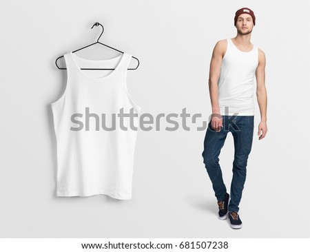 White tank top, sleeveless t-shirt on a man in jeans and hat, isolated, mockup. Hanging tank top, against empty wall.