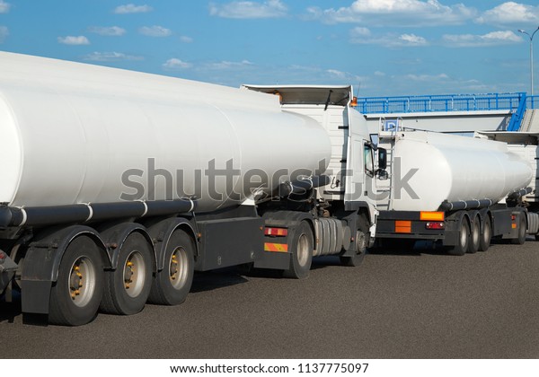 white tank trucks on the road,\
clear space on the cistern side, oil transportation\
concept