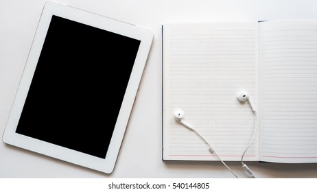 White Taplet And Earphone On Booknote White Background