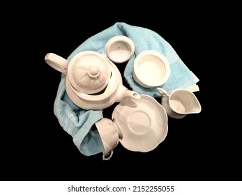 The White Tea Set Includes A Teapot, Creamer Jar, Sugar Jar, Teacup And Coaster. Which Is A Ceramic Cookware And Light Blue Wipes All This On A Black Background.