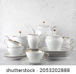 White tea set on a white background. Teapot, cream, sugar bowl, cups, saucers, plates on the table. Porcelain dishes. For six persons.
