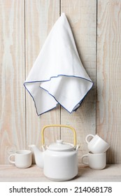 A White Tea Set On A Rustic Whitewashed Setting With A Towel Hanging On The Wall. 