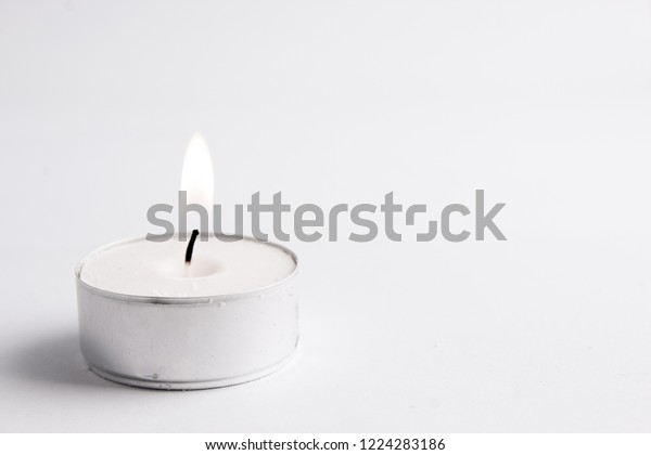 white tealight candle isolated in white, clean\
backgroung; with flame
