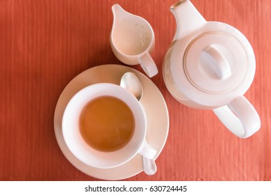 White Teapot Set On An Orange Table Runner