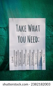White tear-off stub note with text 'Take what you need' on emerald wall. 