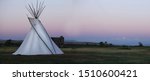 A white teepee on the Montana high plains glows at dusk.