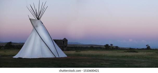 A white teepee on the Montana high plains glows at dusk.
