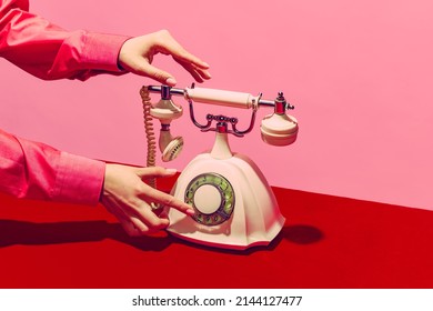 White telephone  Pop art photography  Retro objects  gadgets  Female hand holding handset vintage phone isolated pink   red background  Vintage  retro 80s  70s style  Complementary colors 