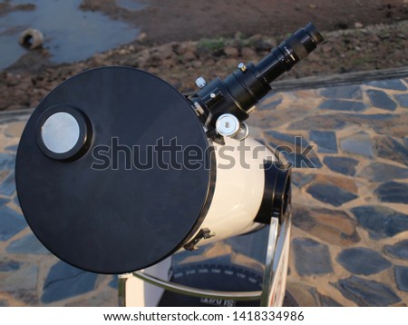 White telescope for watching close-up stars Installed on a stone courtyard on the banks of a public reservoir On a cement background and ground 