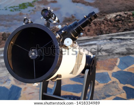 White telescope for watching close-up stars Installed on a stone courtyard on the banks of a public reservoir On a cement background and ground