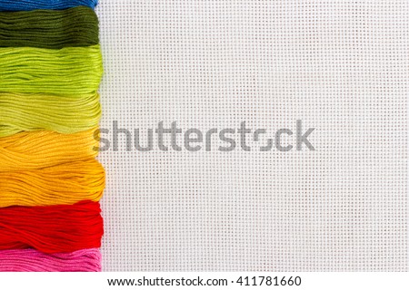 White textile canvas with colorful threads and a blank space as a background.