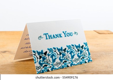 White thank you card with blue letters with note written by hand