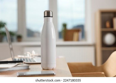 White thermos bottle at wooden table indoors - Shutterstock ID 2247180335