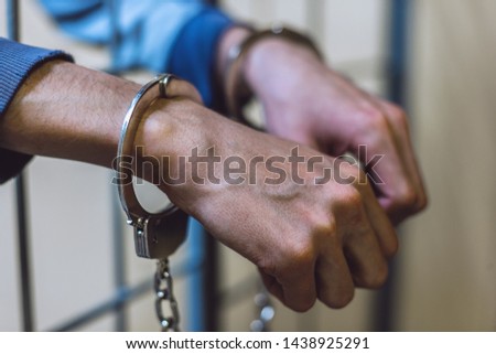 White thin venous hands in handcuffs close-up against the background of the lattice. Punishment for a crime and violation of the law