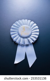 White third place winner of the socket with a pleated ribbon on a dark background