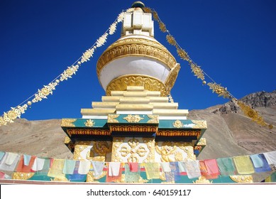 White Tibetan Buddhist stupa decorating with prayer flag in Tabo village, blue sky and mountain background, Spiti Valley, India 