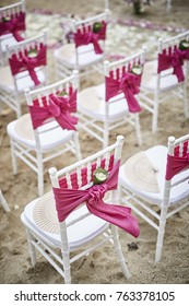 White Tiffany chairs pink cover with banana leaf confetti on the beach