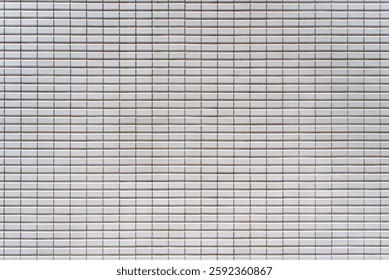 A White tiled wall with grid pattern, featuring small square tiles and subtle grout lines, creating clean and modern aesthetic. Ideal for various design applications