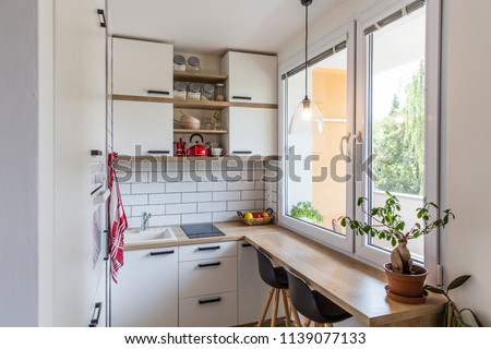 White tiny modern kitchen with red components, reconstruction, cosy small panel house in Prague, Czech Republic