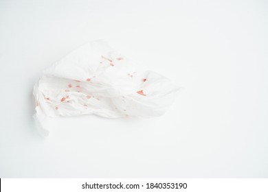 White tissue with blood stains on a wooden table.