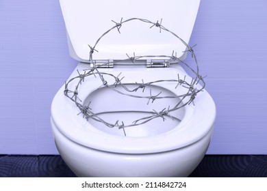 white toilet bowl with an open lid and heart-shaped barbed wire on a black tiled floor and purple walls. Proctology medical concept. High quality photo