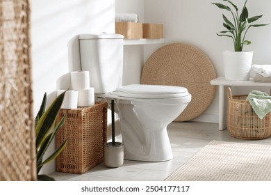 White toilet bowl, paper rolls and houseplants in bathroom