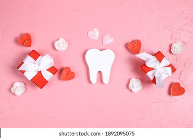 White tooth with gifts, hearts and roses on a pink background. Dental Valentine card. Valentine's day concept.  