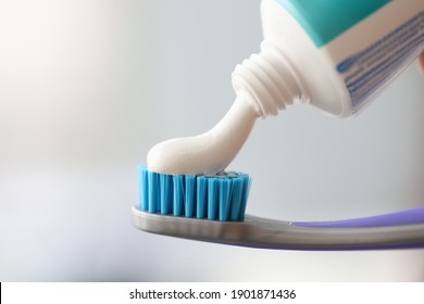 White toothpaste is applied to toothbrush. Oral Care Concept - Powered by Shutterstock