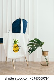 White Tote Bag Mockup Hanging On A Blue Velvet Chair