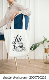 White Tote Bag Mockup Hanging On A Blue Velvet Chair