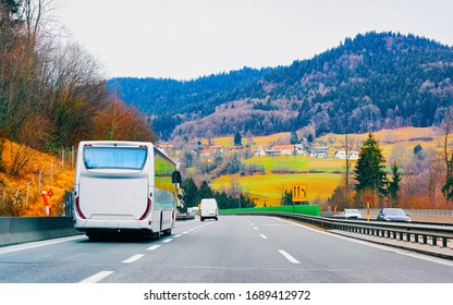 White Touristic Bus In Road. Tour Modern Shuttle Bus Back On Highway. Urban Transport With Driver. Excursion Long Transit Vehicle.