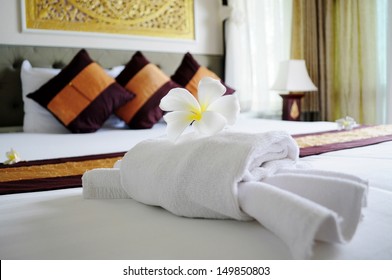 White Towel In Crab Shape And A Frangipani Flower On White Bed In Relaxation Bedroom Of Luxury Boutique Hotel