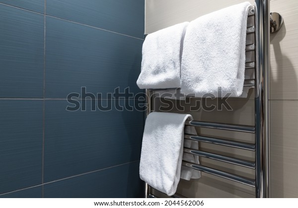 White towels are dried on a heated towel rail in\
the bathroom