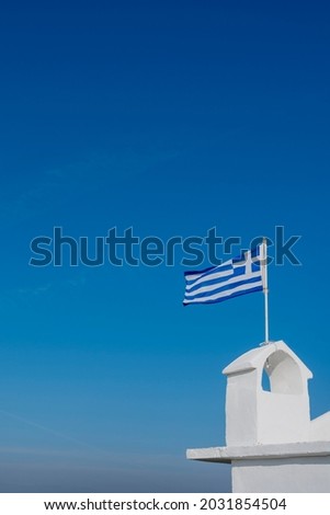 white tower with a Greek flag on a whitewashed-fronted orthodox hermitage near Alexandroupolis in Greece