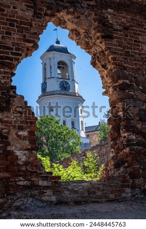 The White Tower in Vyborg, formerly the bell tower of the Old Cathedral, then the Clock Tower and simultaneously the watchtower of the city fire brigade.   tower through the ruins of an old wall.