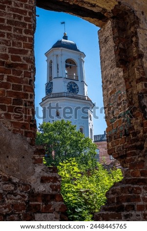 The White Tower in Vyborg, formerly the bell tower of the Old Cathedral, then the Clock Tower and simultaneously the watchtower of the city fire brigade.   tower through the ruins of an old wall.